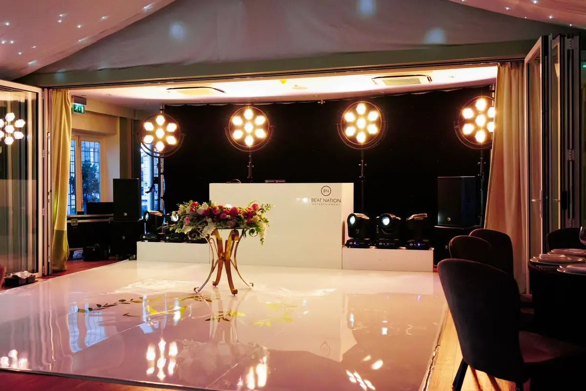 A white DJ booth dressed with florals under flower-shaped lights