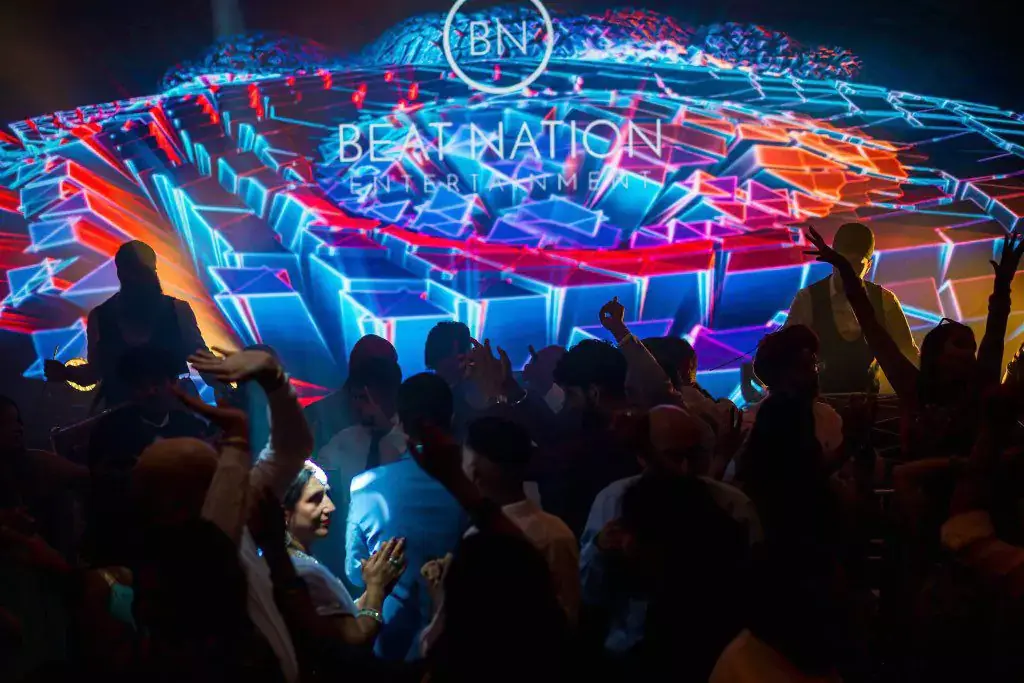 A packed dance floor in front of a Beat Nation LED floor display