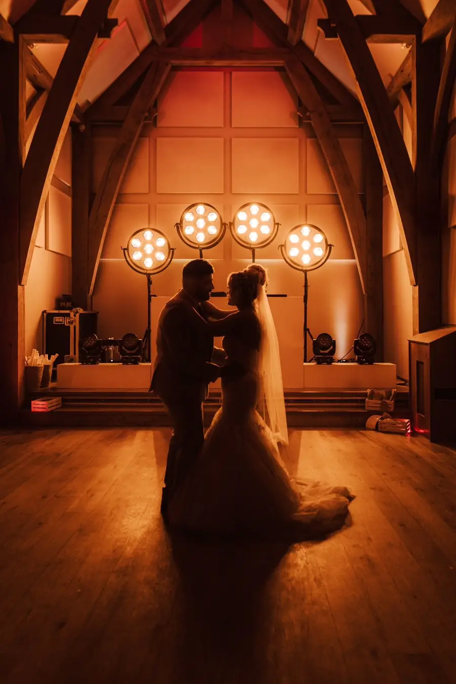 A couple silhouetted under warm stage lights for their first dance