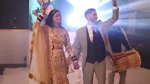 A couple making their entrance with a dhol player behind them