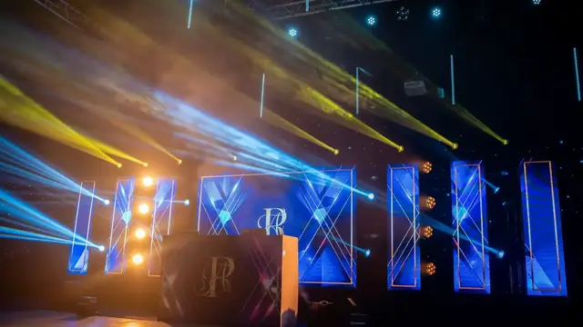 Blue and gold lighting beams over a DJ booth